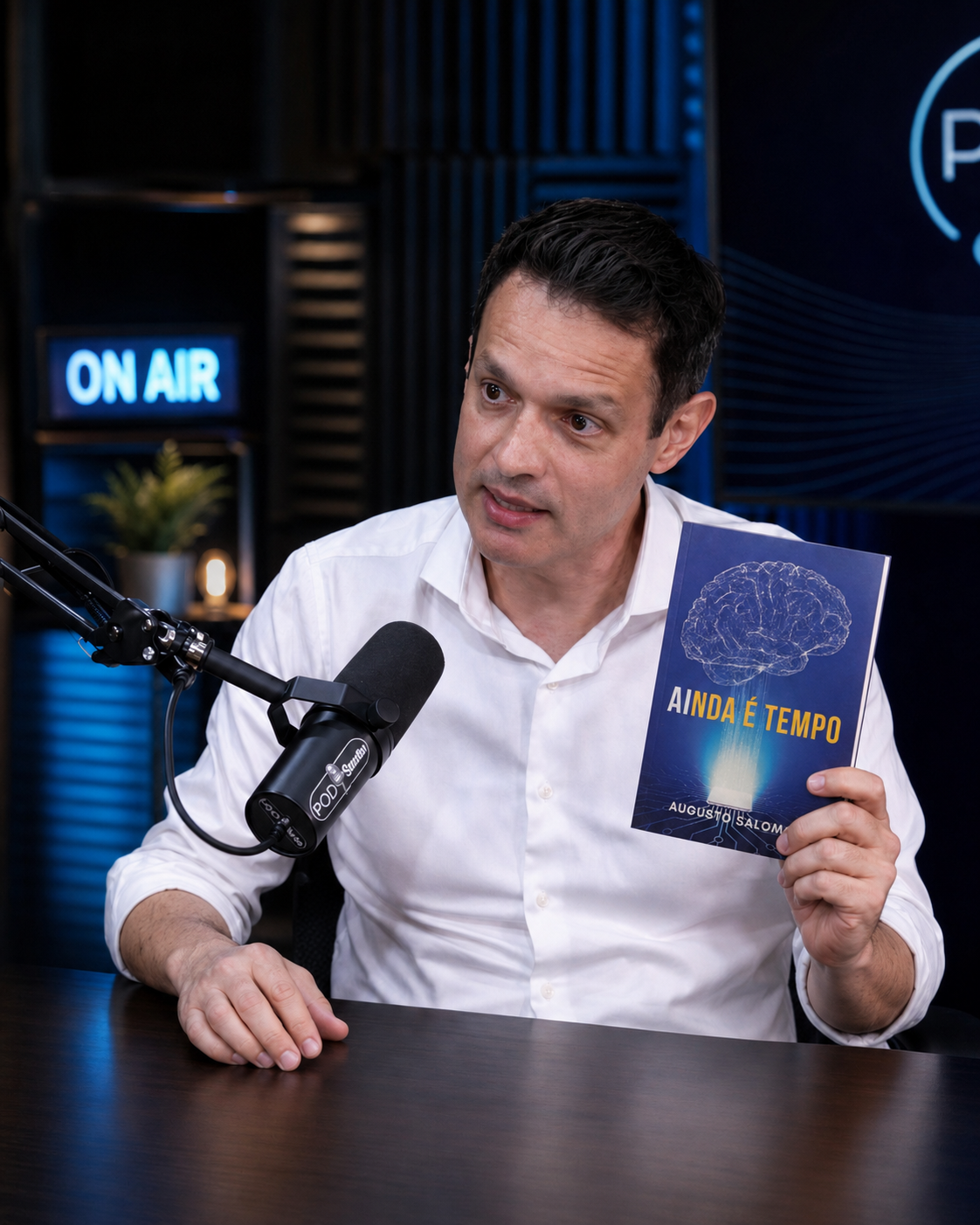 Augusto Salomon em estúdio de podcast segurando o livro AInda é Tempo