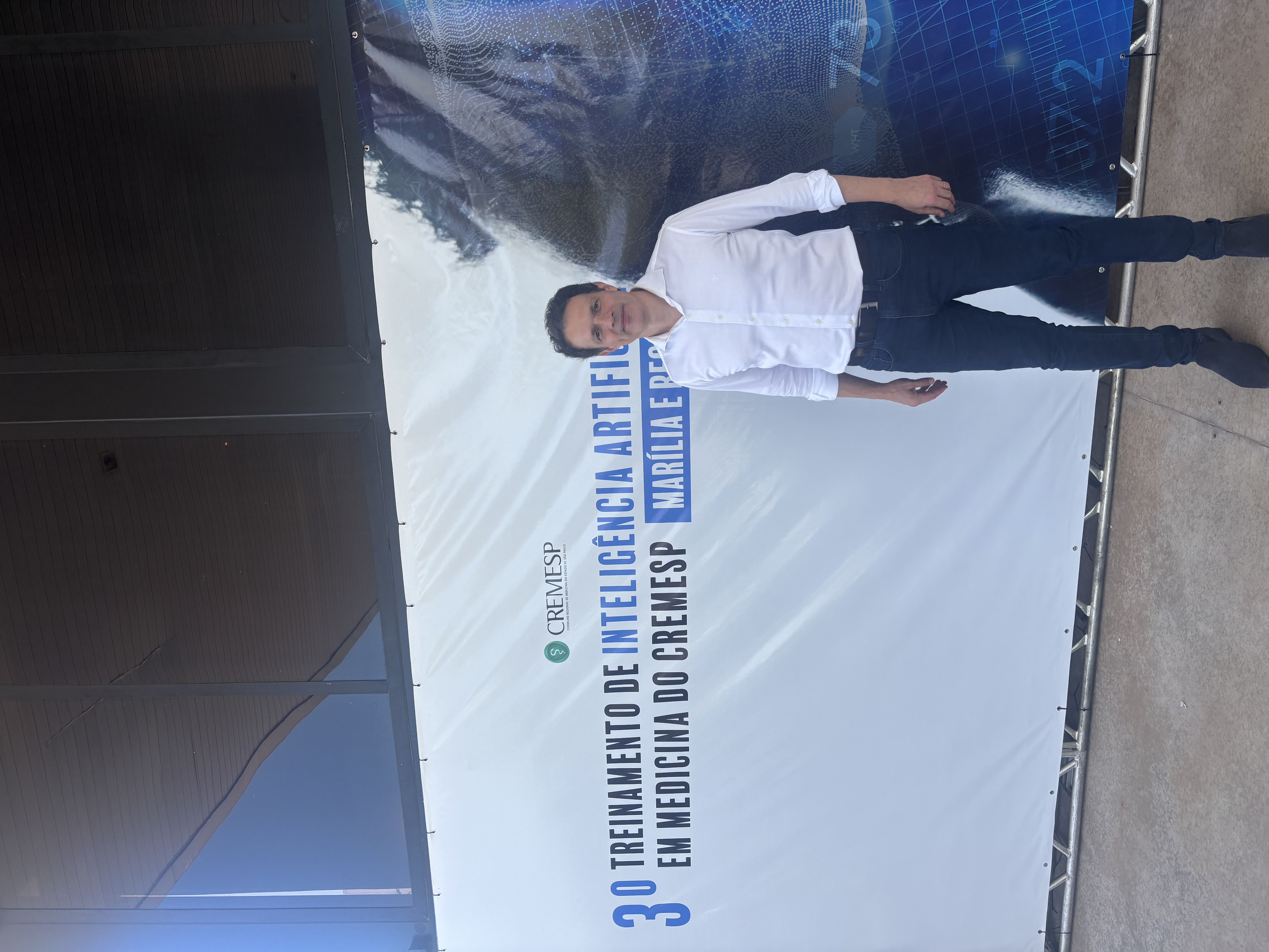 Augusto Salomon diante do banner do 3º Treinamento de IA em Medicina do CREMESP em Marília