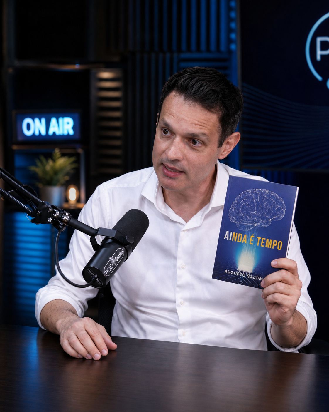 Augusto Salomon em estúdio de podcast segurando o livro AInda é Tempo